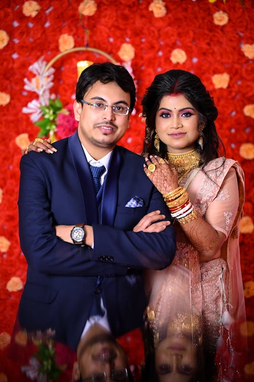 A man and woman posing for a photo in front of a red background