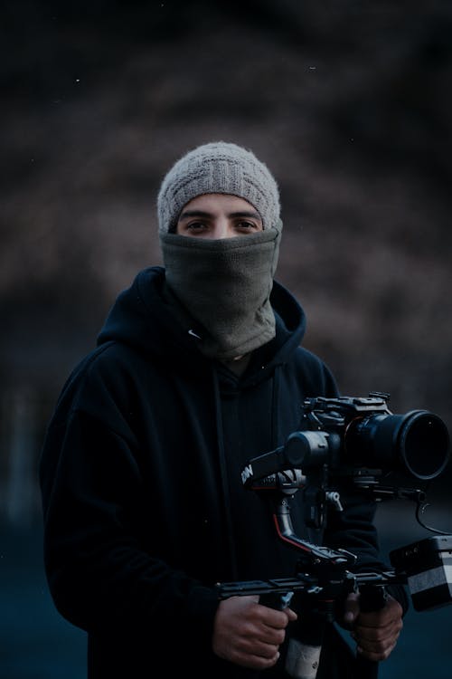 portrait of man in hat and buff holding camera