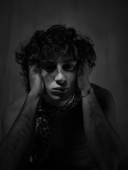 Black and white portrait of a young man with curly hair in a thoughtful pose.