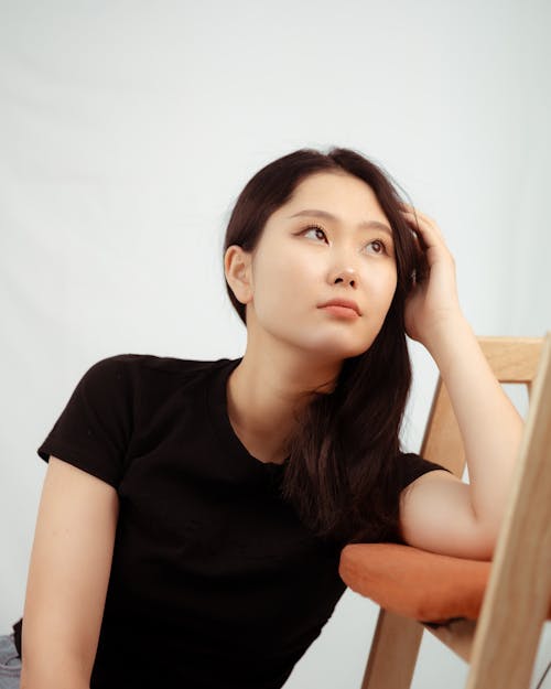 Woman Wearing a Black T-Shirt, Leaning against a Chair