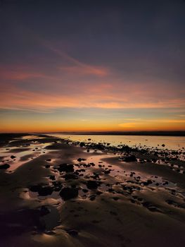 A tranquil beach scene at sunset showcasing vibrant skies and ocean reflections.