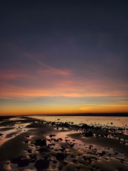 Captured at sunset, this rocky beach scene reveals vibrant colors reflecting in tidal pools.