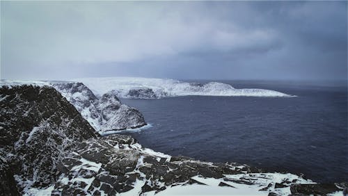 Dark Sea and a Rocky Coast in Snow