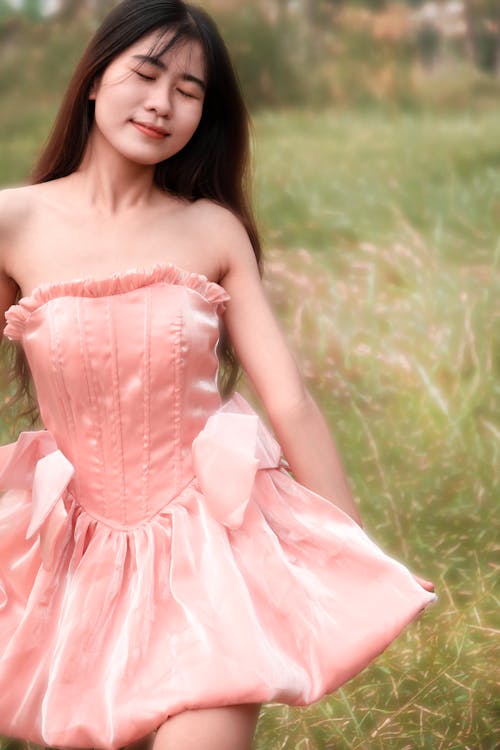 A young woman in a pink dress is posing