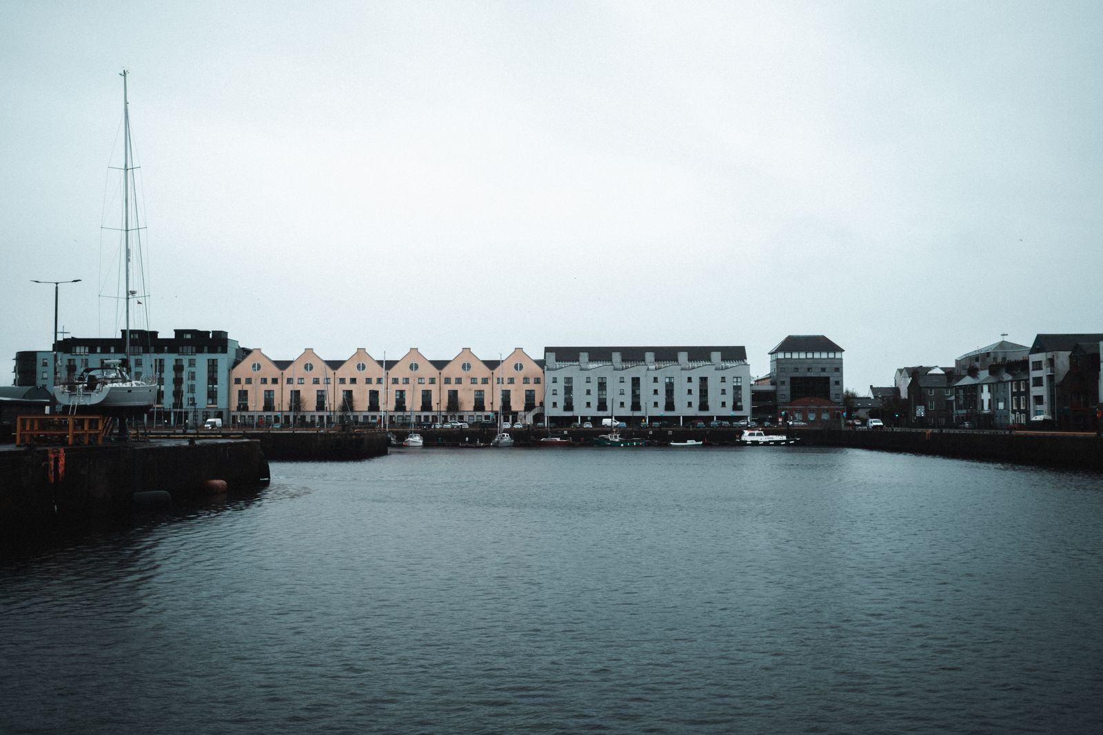 View of Galway Harbor with colorful townhouses and boats, showcasing urban waterfront architecture