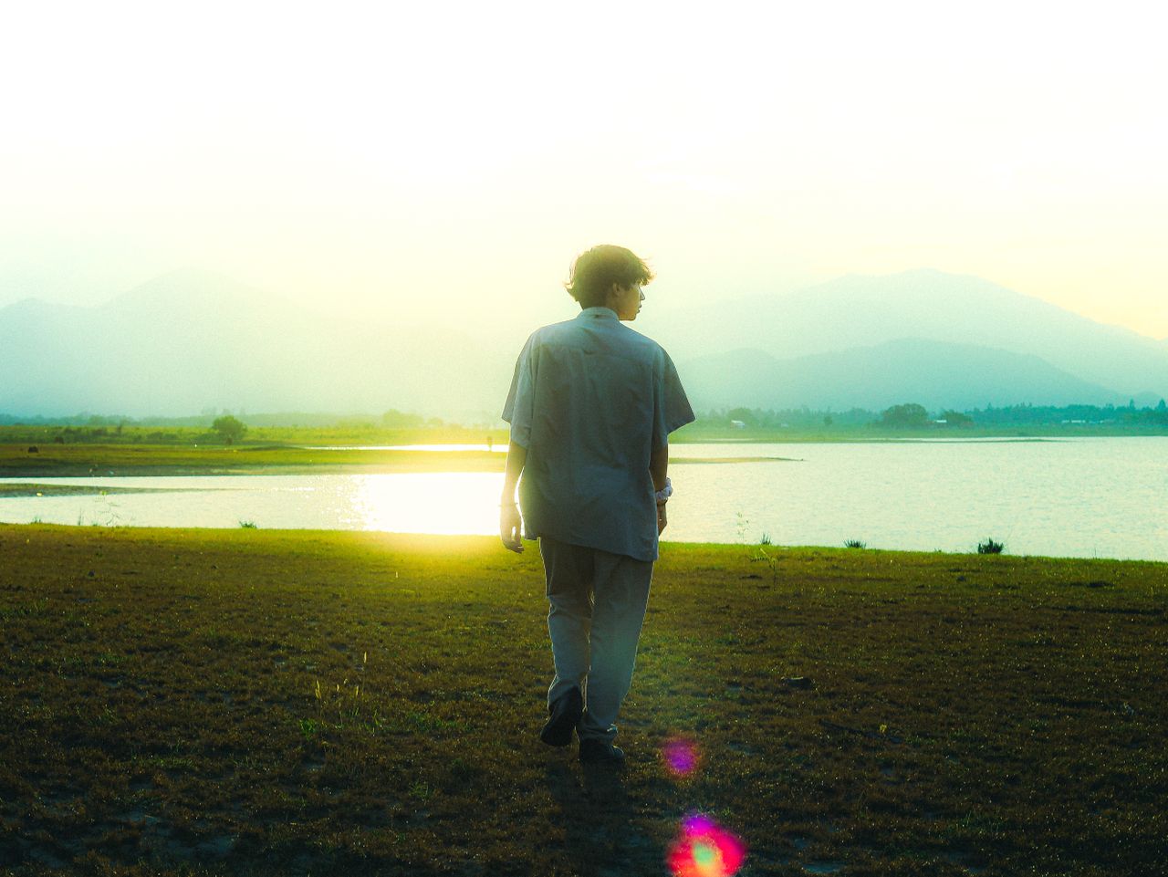 a young man walks by a tranquil lake during sunset embodying peace and