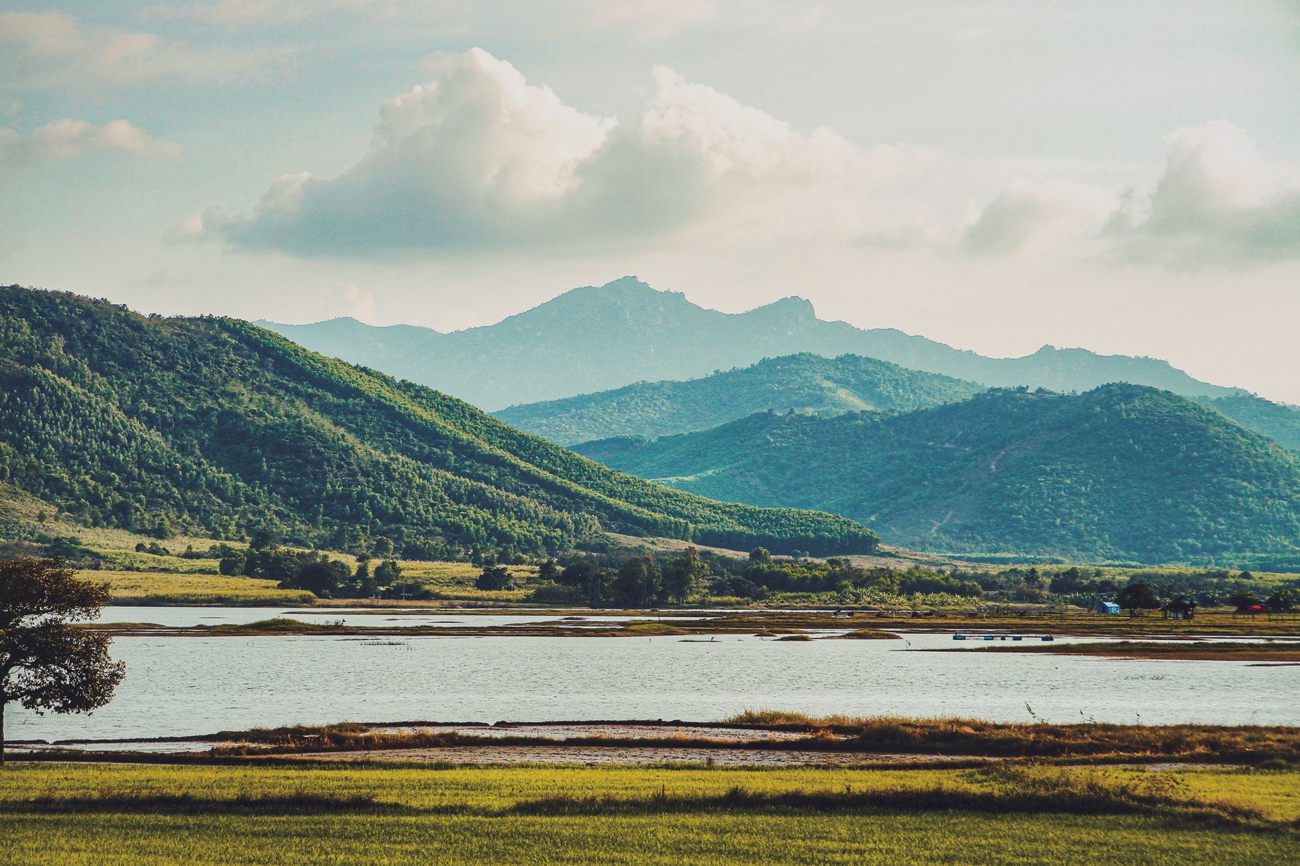 Tranquil view of lush green mountains with a peaceful lake in the foreground.