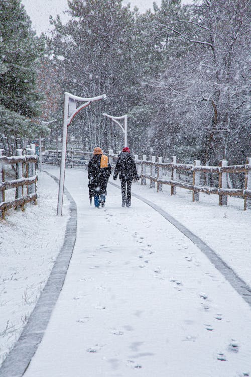 Two people walking on a snow covered path