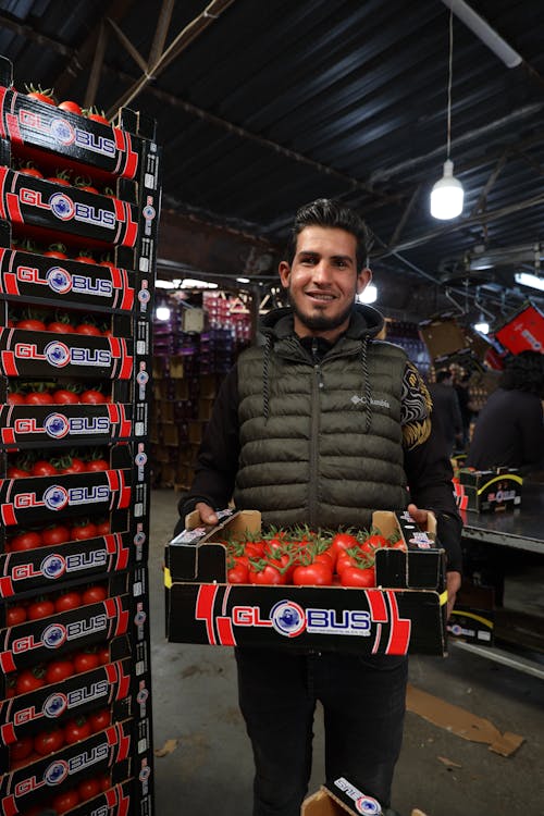 A man holding a box of tomatoes in a store