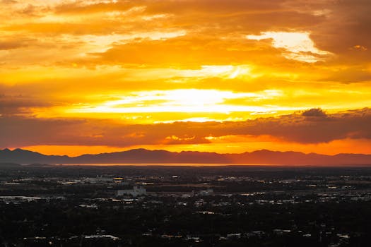 Majestic golden sunset painting the sky over an expansive cityscape with mountains in the distance.