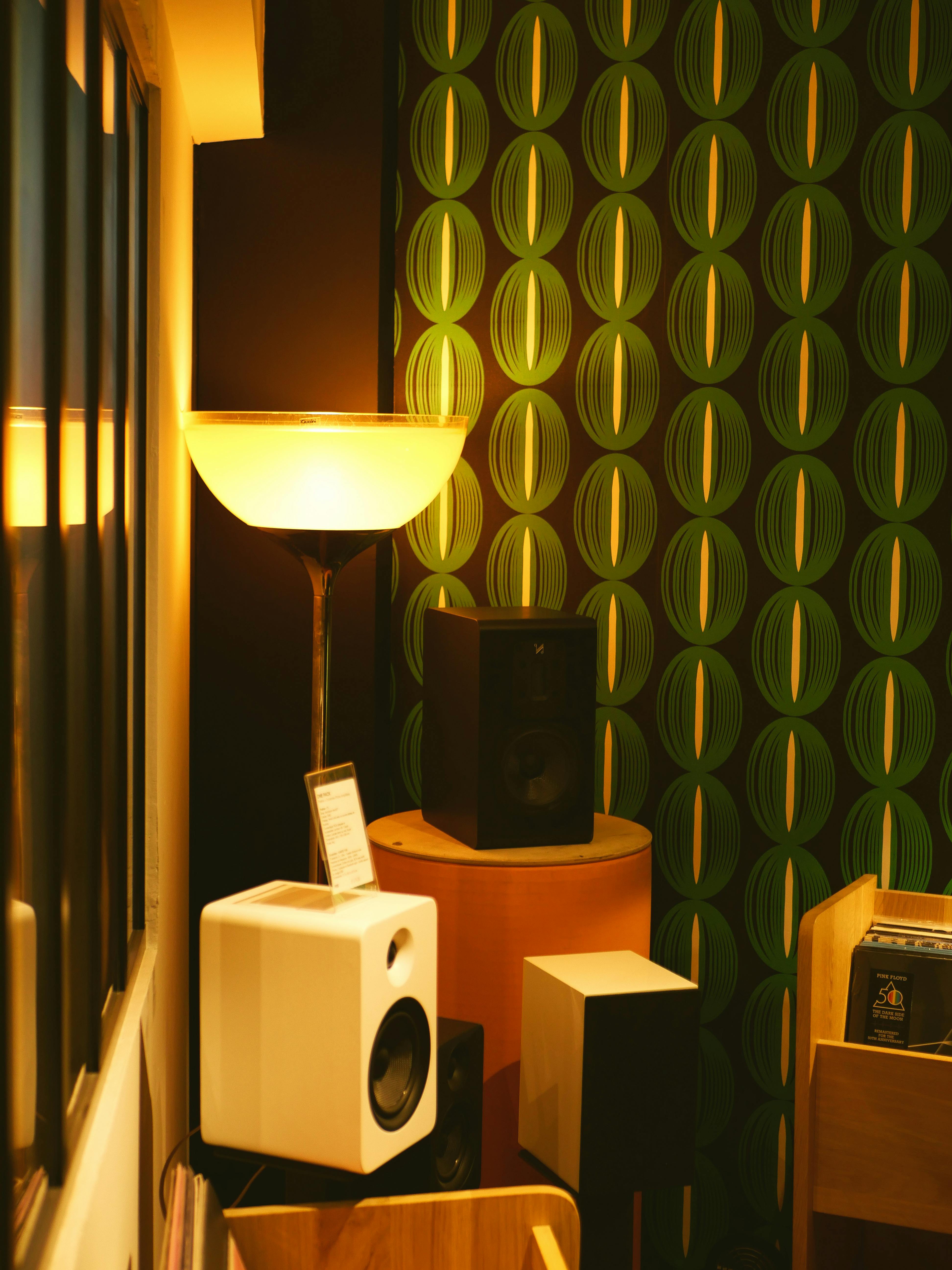 Contemporary room with modern speakers, floor lamp, and geometric wallpaper pattern.