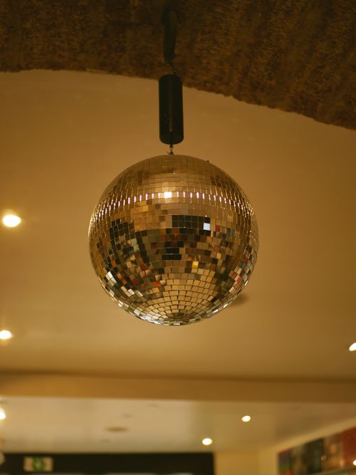Free Close-up of a shiny disco ball reflecting warm light in an indoor space, creating a nostalgic ambiance. Stock Photo