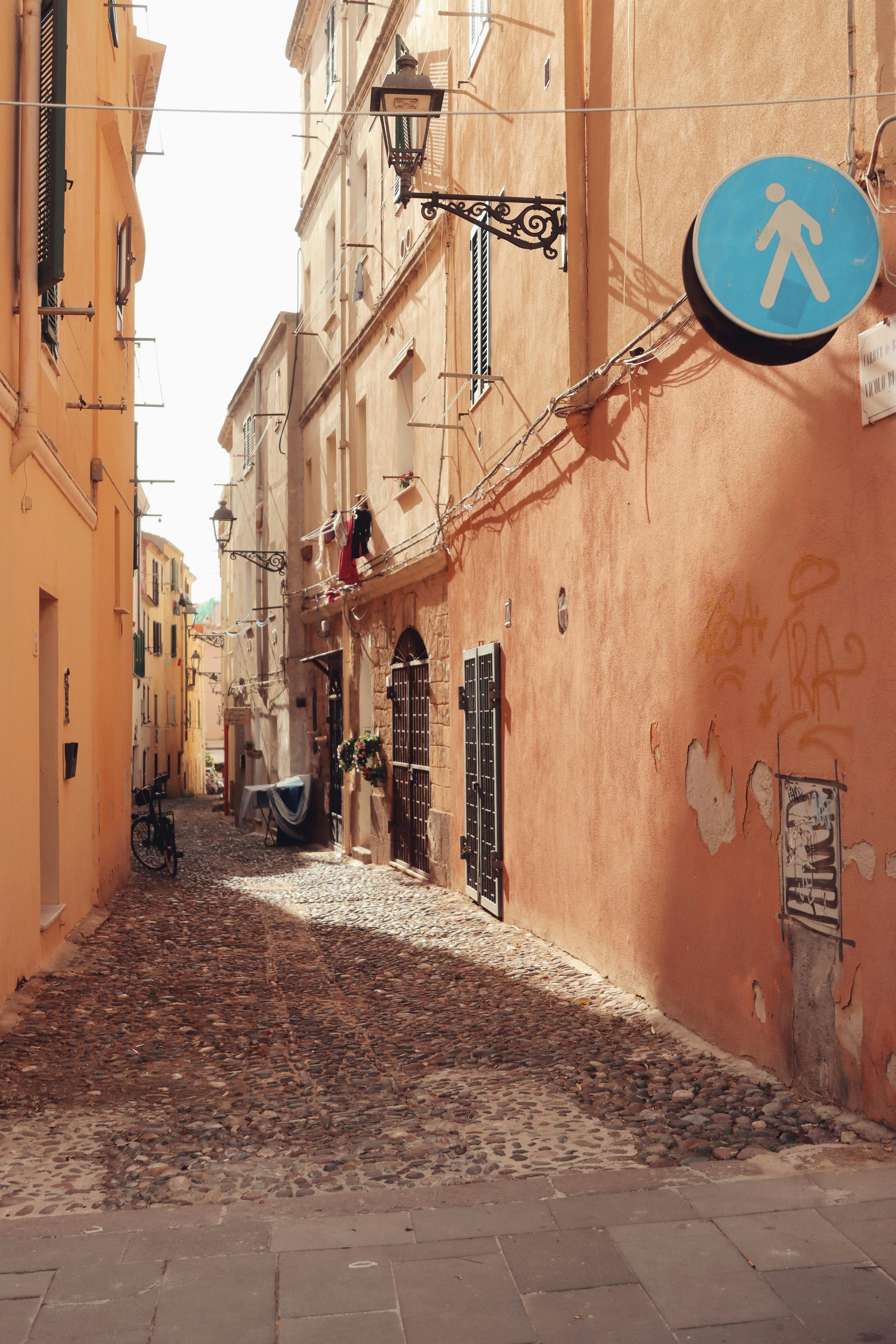 Discover a serene cobblestone street in historic Alghero, Sardinia, Italy, with colorful buildings and timeless charm.