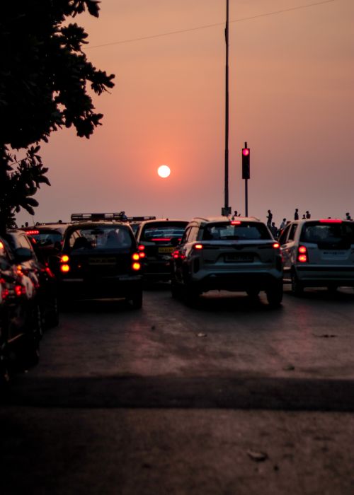Free Dramatic sunset over a busy Mumbai street, capturing silhouetted cars and a vibrant orange sky. Stock Photo