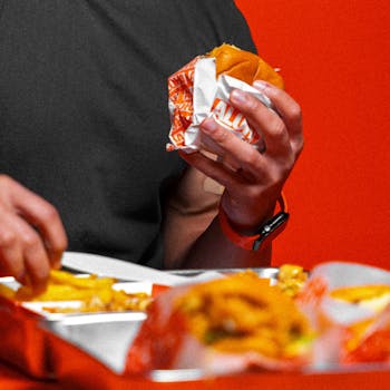 Close-up of a person enjoying a burger and fries at a restaurant, depicting casual dining.