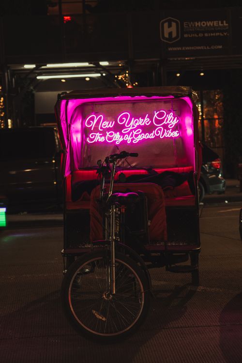 Free Neon-lit pedicab on New York City street at night, exuding urban charm. Stock Photo