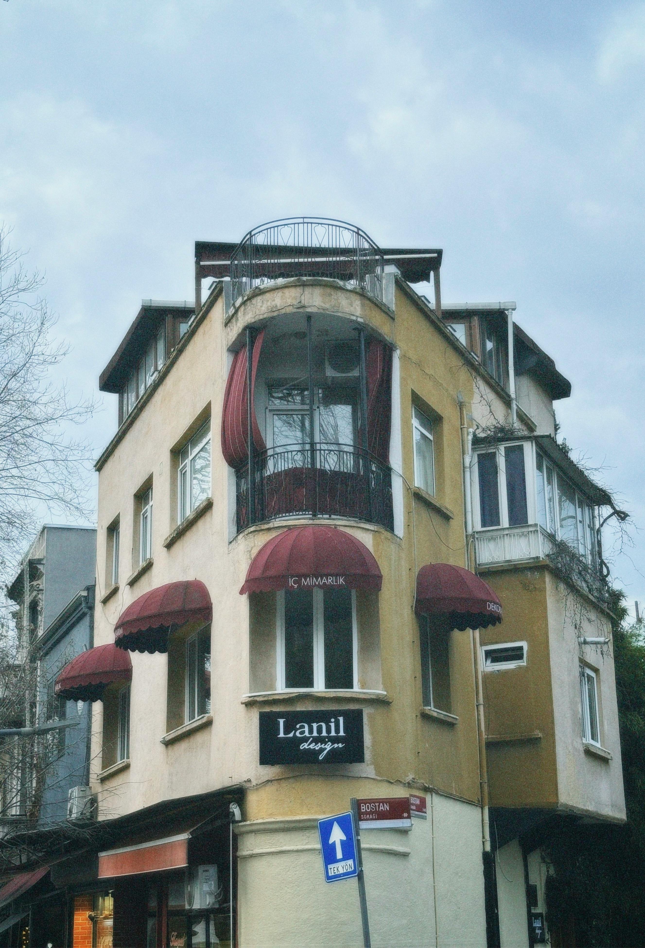 Free Charming corner building with colorful awnings and classic architecture under cloudy skies. Stock Photo