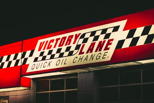 A vibrant sign for Victory Lane Quick Oil Change at night with checkerboard design. 20004532