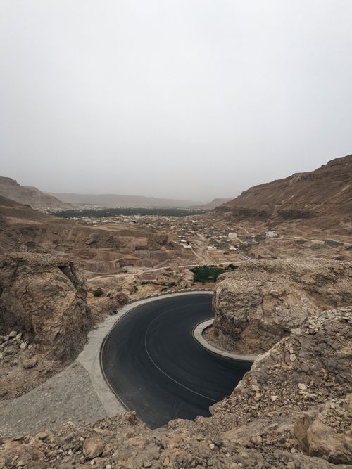 Free A winding road through rocky desert landscape under a misty sky, perfect for travel and adventure themes. Stock Photo