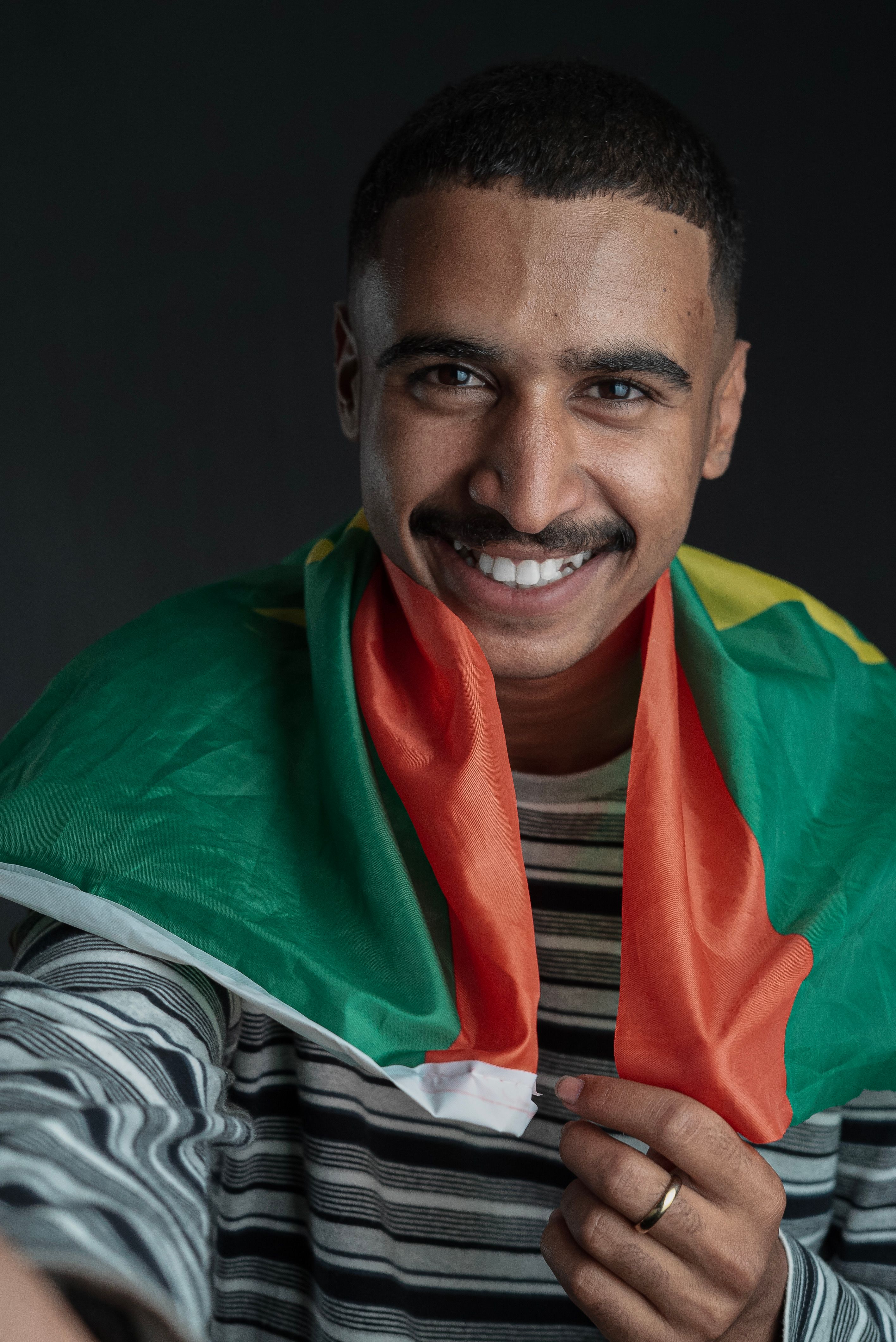 A young man smiles and holds the Mauritania flag in a vibrant portrait.