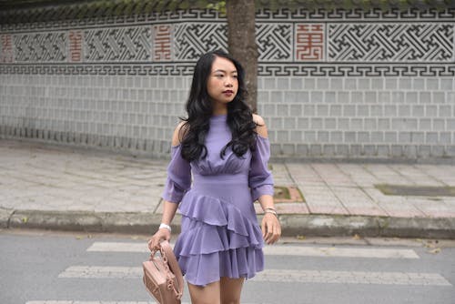A woman in a purple dress and heels walking down the street