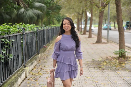 A woman in a purple dress and heels walking down the sidewalk