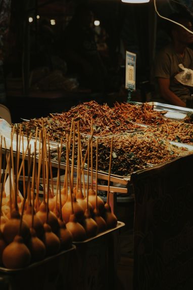 Night market stall with trays of skewers under warm light — photo by Namfon Sasimaporn on Pexels