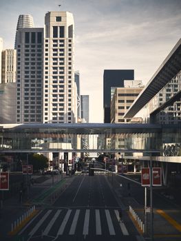 View of a city skyline with skyscrapers and a glass pedestrian bridge on a clear day.