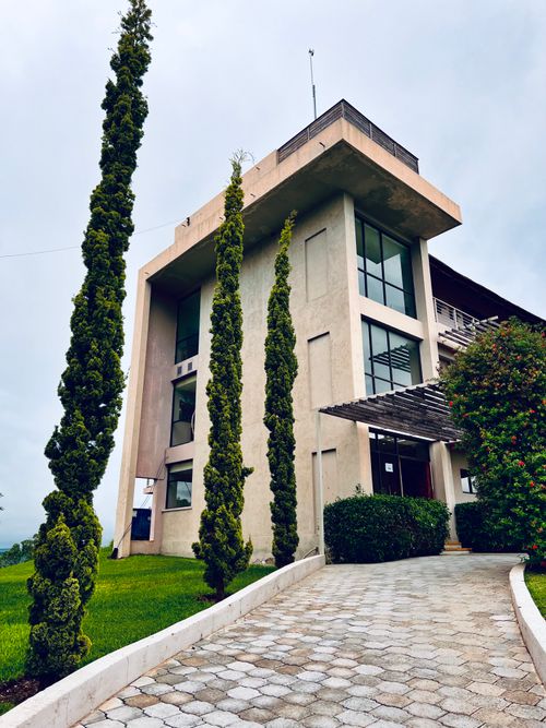Free A contemporary concrete building complemented by elegant landscaping and a paved walkway under a cloudy sky. Stock Photo