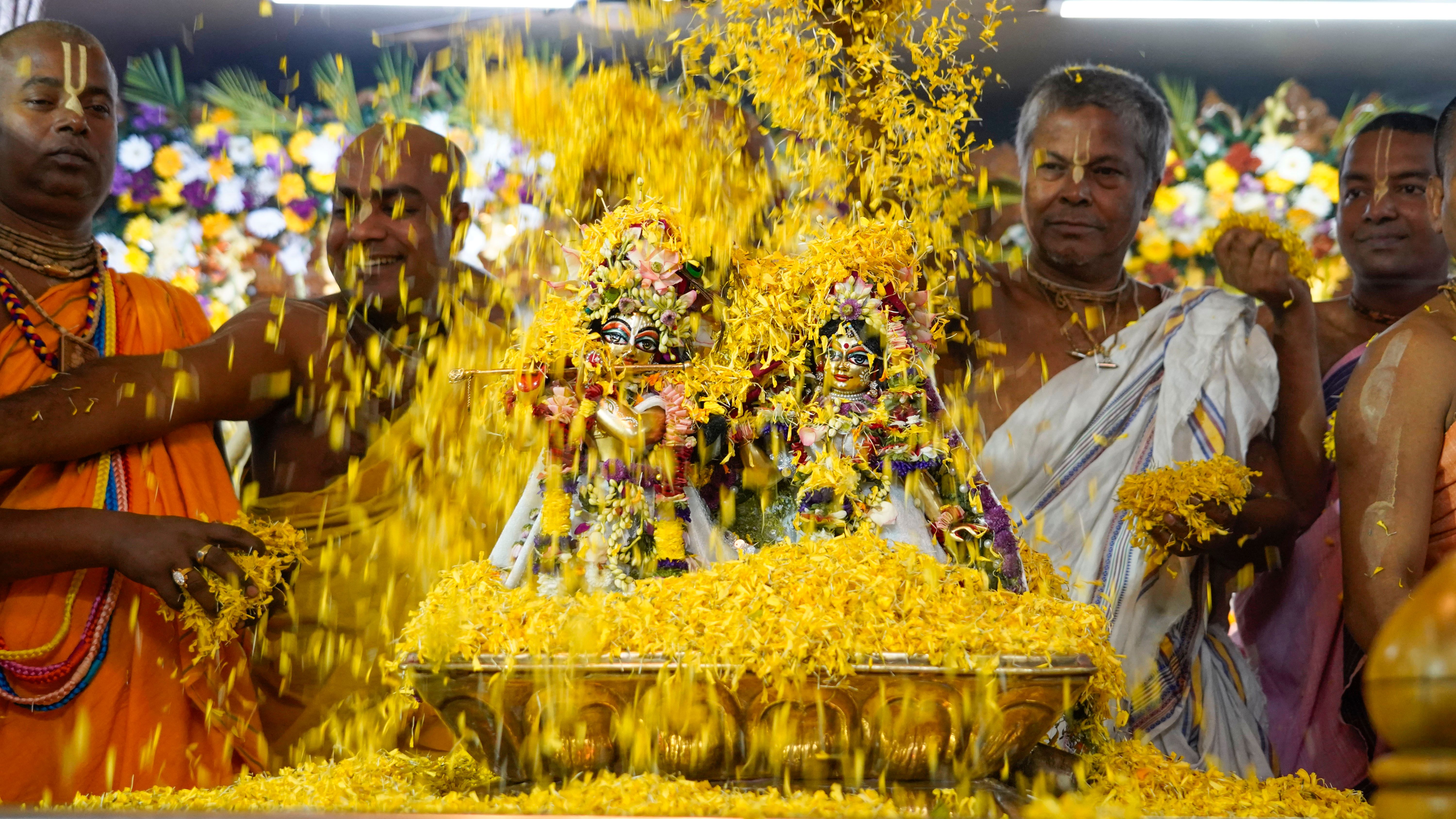 Hindu men performing a lively traditional ceremony with vibrant yellow flowers.