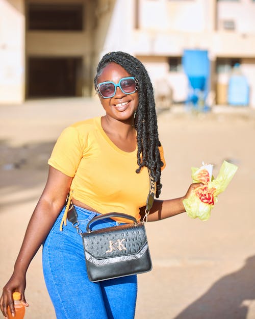 A woman in yellow shirt and blue jeans holding a bag