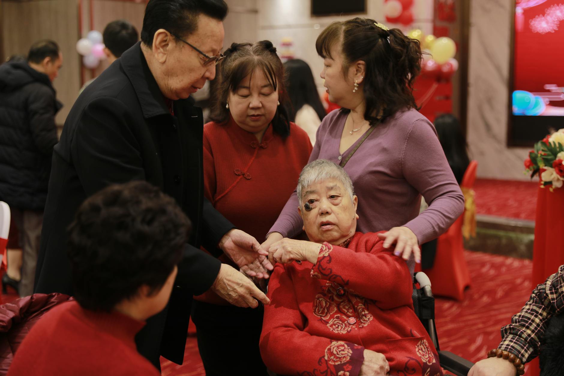 A family gathering indoors during a traditional Asian ceremony with elderly and adults.