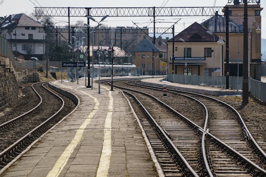 Curved railway tracks at Krynica-Zdrój station with scenic backdrop.