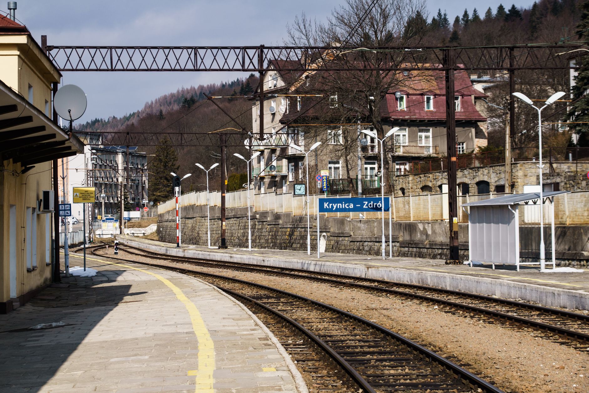 Scenic view of Krynica-Zdrój train station surrounded by mountains and architecture.