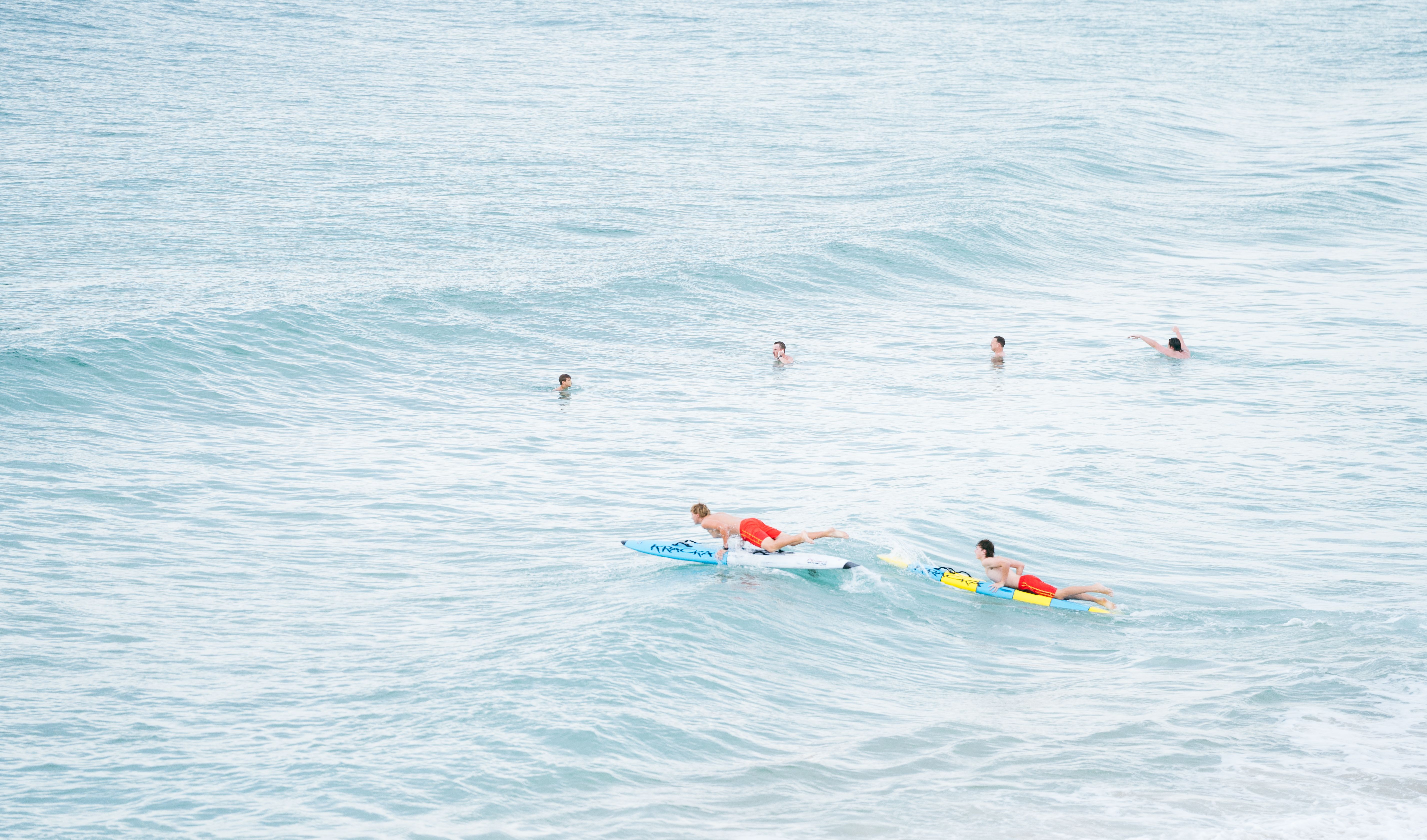 Surfers ride the waves at Wollongong Beach in Australia, captured in a vibrant summer scene.