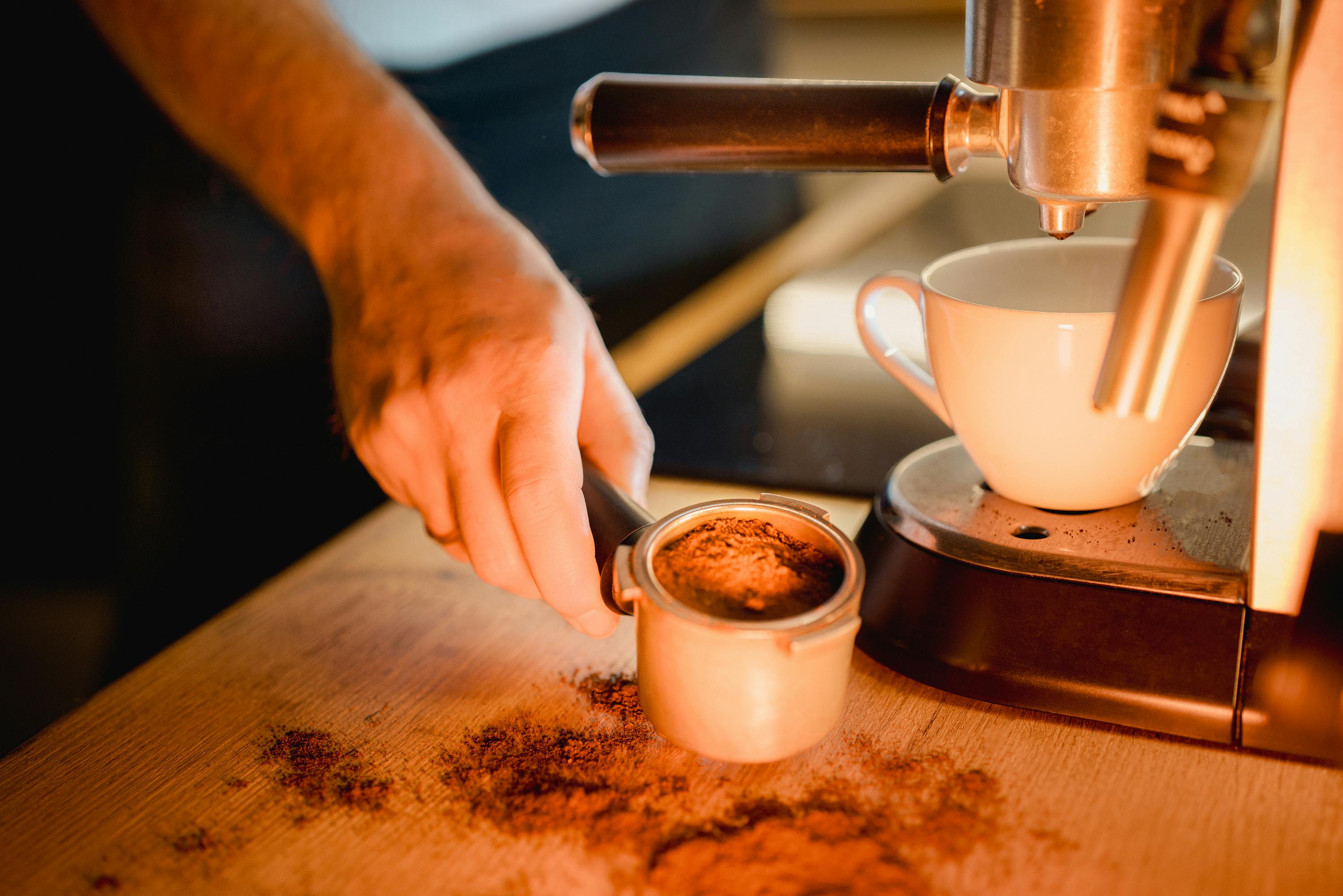 A hand prepares an espresso with a portafilter, showcasing precision in coffee making.
