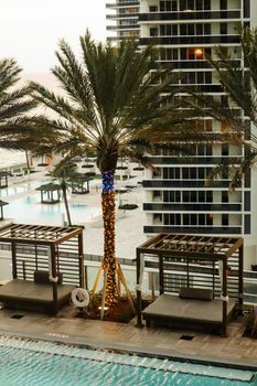 A serene view of a luxury resort pool with palm trees and cabanas, ideal for a summer vacation.