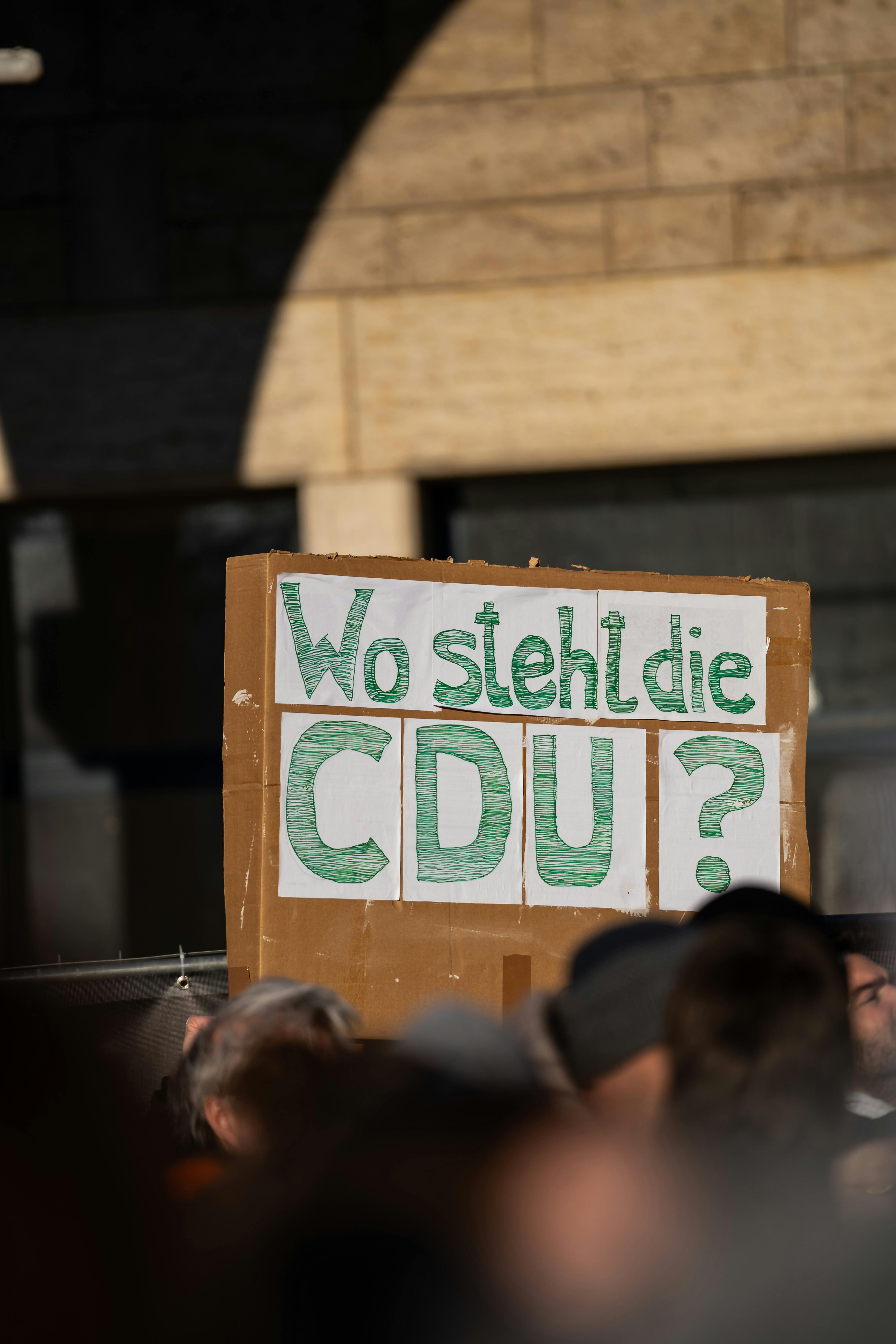 Protest sign questioning CDU stance in Stuttgart, Germany, outdoors.
