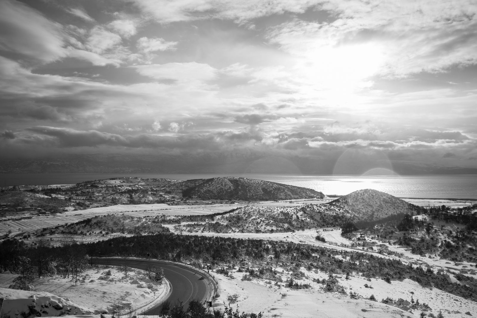 Snow-covered hills above the lakeshore at Pogradec, Albania, under a bright winter sky