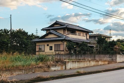 Free A serene view of a traditional Japanese house with a slate roof set against a cloudy blue sky. Stock Photo