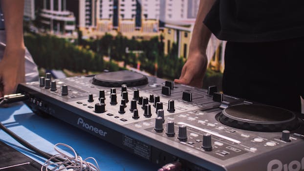 A DJ mixes music on a modern console outdoors, adding dynamic sound to an urban event.