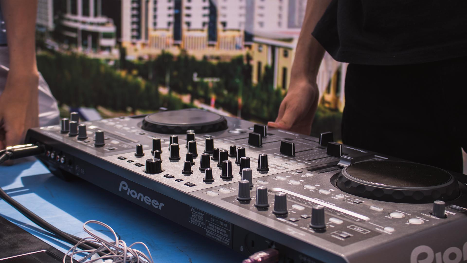 Person in Black T-shirt Standing in Front of Black Dj Mixer