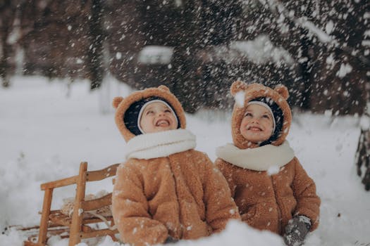 Two kids in bear costumes playing joyfully in the snowy forest with sleds.