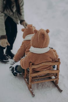 Two children in bear costumes enjoying a snowy sled ride with a parent in winter.