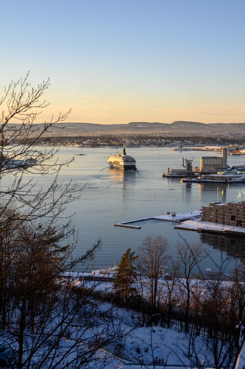 Free Scenic view of a cruise ship sailing in the Oslo fjord during sunset with snowy surroundings. Stock Photo
