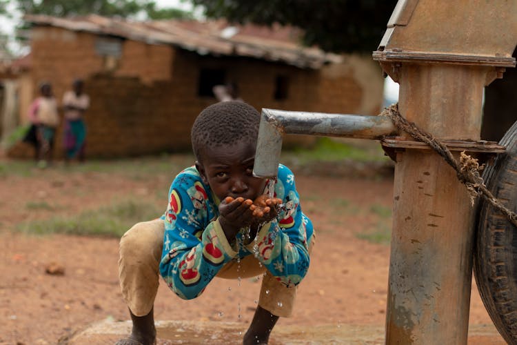 Boy Drinking Water In Village