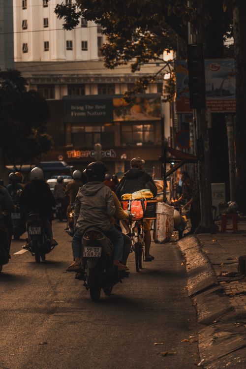 Free People commuting on motorcycles and bicycles in a city street during the evening. Stock Photo