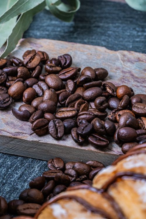 Free A detailed shot of fresh brown coffee beans on a rustic wooden board, perfect for food and drink themes. Stock Photo