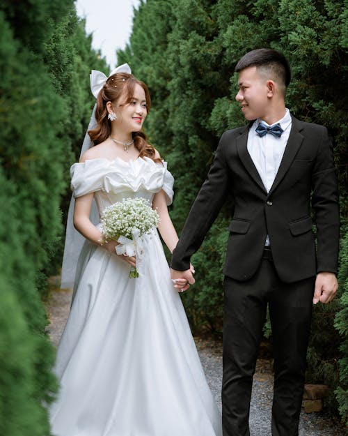 A bride and groom walking through a forest
