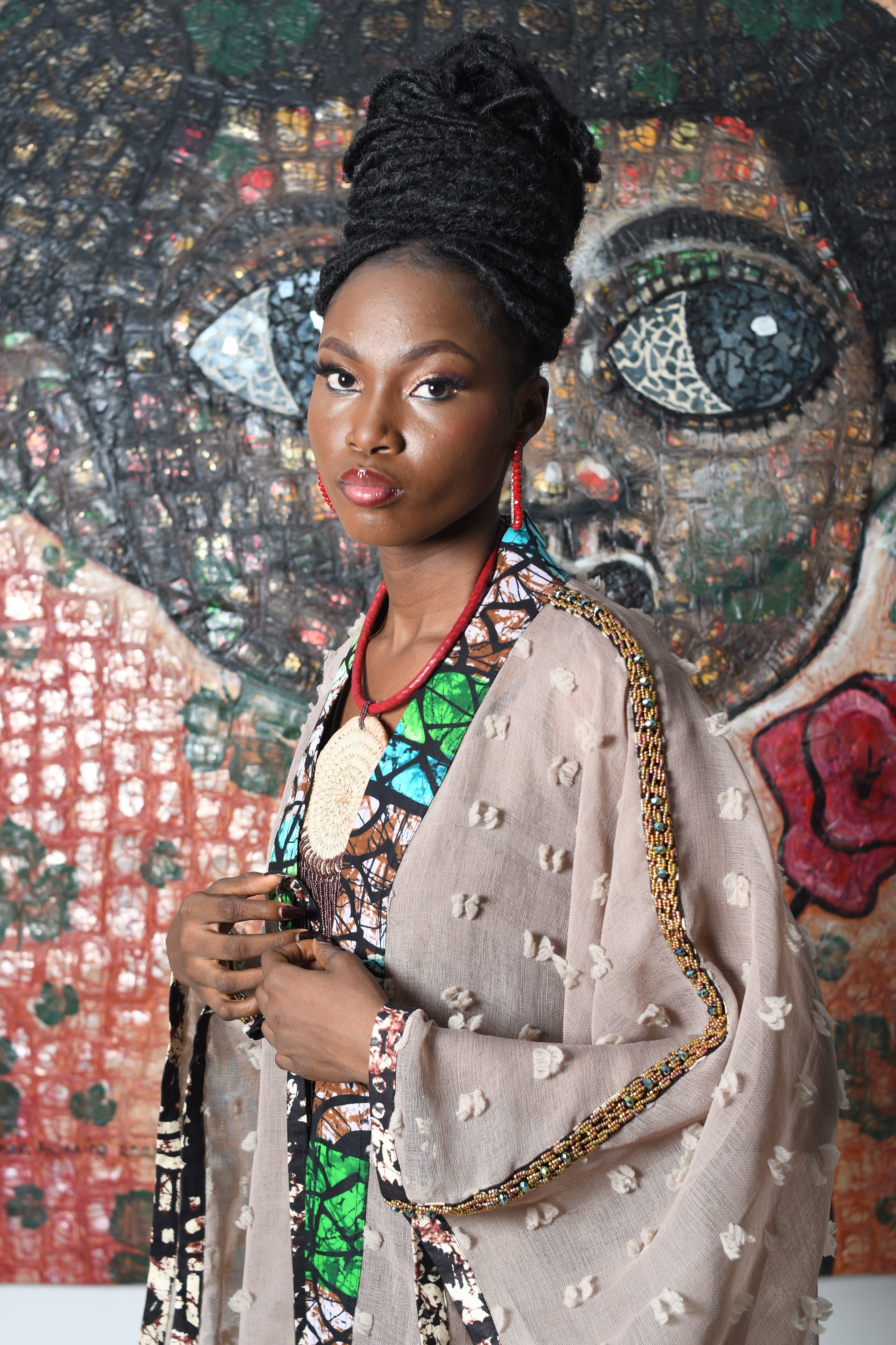 Fashion portrait of a woman in traditional attire against a mosaic backdrop, showcasing elegance and style.